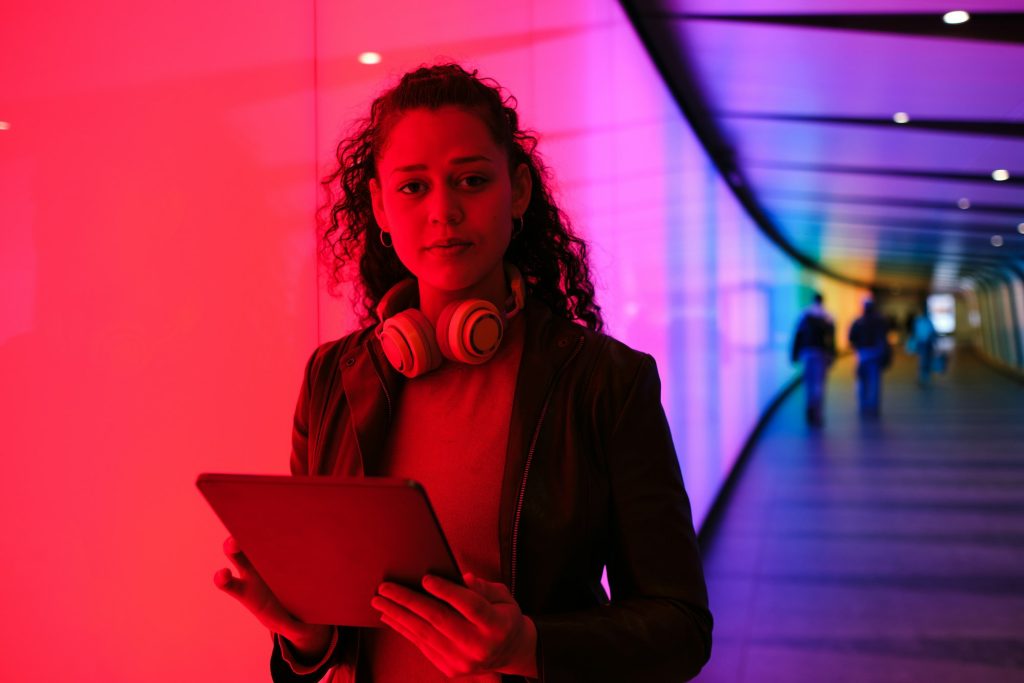 Young woman using digital tablet in colorful futuristic tunnel